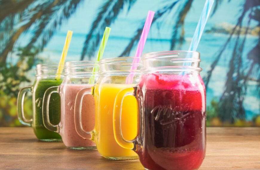 Vibrant fruit juices in mason jars with colorful straws, perfect for a summer refreshment.